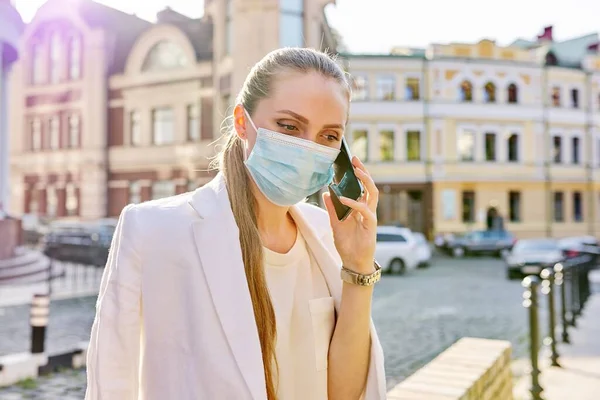 Retrato de una joven mujer de negocios con máscara de protección médica hablando por teléfono celular —  Fotos de Stock