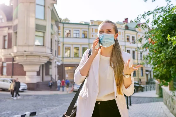 Mujer de negocios joven en máscara de protección médica hablando en el teléfono inteligente —  Fotos de Stock