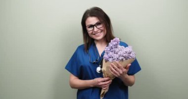 Gülümseyen olgun kadın doktor hemşire çiçek buketi, hediye, kutlama, sağlık çalışanları günü.