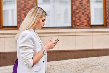 Cep telefonuyla yürüyen genç iş kadını, profil görünümü kopyalama alanı