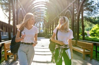 İki mutlu gülümseyen genç kız birlikte yürüyorlar.