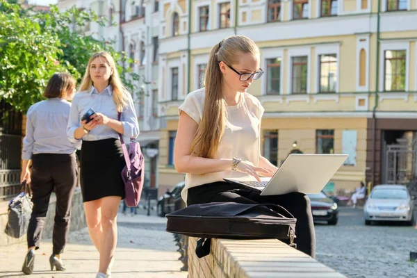 Молодая деловая женщина сидит с ноутбуком, смотрит на экран, работает на открытом воздухе — стоковое фото