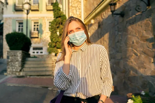 Joven mujer de negocios trabajadora de oficina en máscara de protección médica hablando en smartphone —  Fotos de Stock