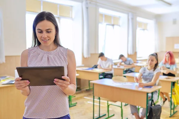 Ritratto di giovane insegnante sorridente e sicura di sé con tablet digitale in classe — Foto Stock