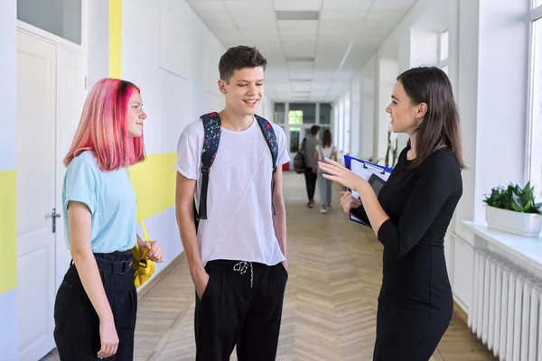 Ομάδα εφήβων μαθητών που συνομιλούν με μια δασκάλα στο σχολικό διάδρομο — Φωτογραφία Αρχείου