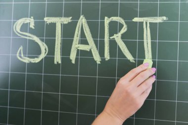 Konsepte başla, kadın eli tebeşirle yazı tahtasına başla.