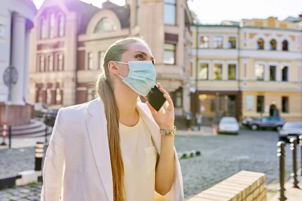 Mujer de negocios joven en máscara de protección médica hablando en el teléfono inteligente —  Fotos de Stock