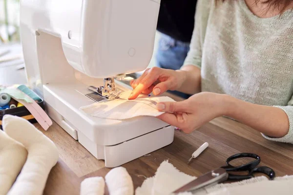 Mujer adulta cose en una máquina de coser sentada en casa en la mesa — Foto de Stock