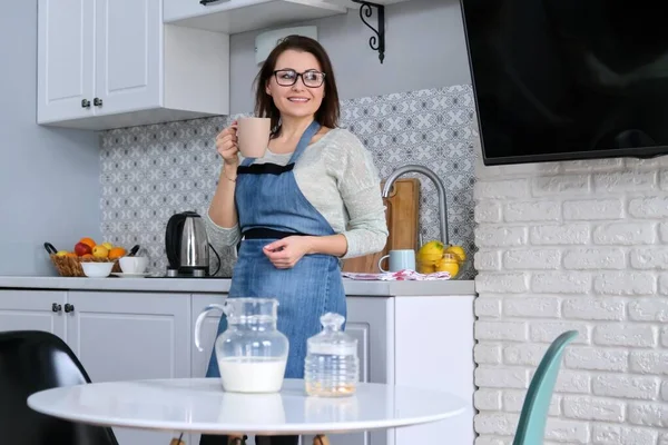 Retrato de mujer madura ama de casa en un delantal en casa en la cocina — Foto de Stock