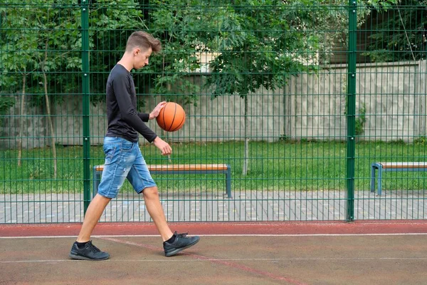 На відкритому повітрі портрет хлопчика-підлітка, який грає у вуличний баскетбол, копіює місце — стокове фото