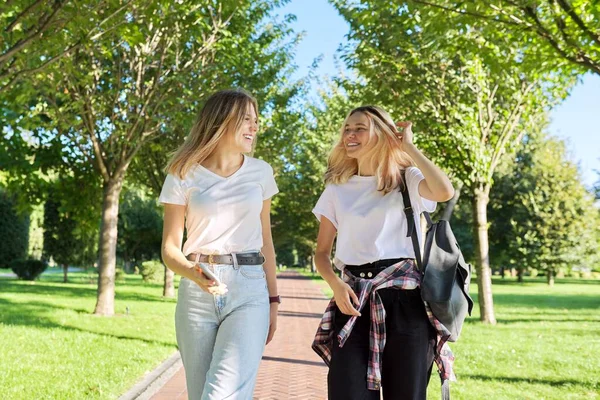 İki güzel, mutlu genç kız. 17-18 yaşlarında. Parkta birlikte yürüyorlar. — Stok fotoğraf