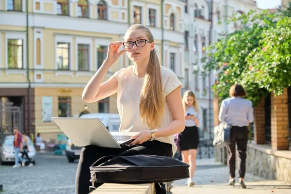 Серьезный молодой бизнесмен в очках с ноутбуком на открытом воздухе — стоковое фото