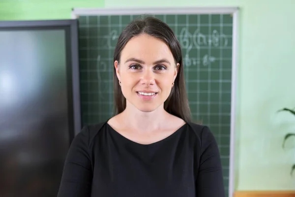 Close-up rosto de jovem professora perto de quadro-negro e tela digital em sala de aula — Fotografia de Stock