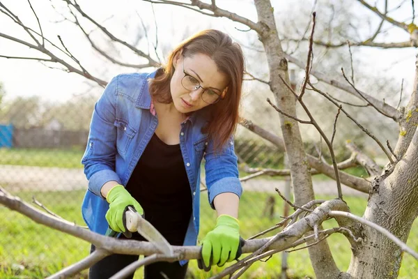 Vrouw tuinier in handschoenen met tuin zagen takken snoeien — Stockfoto