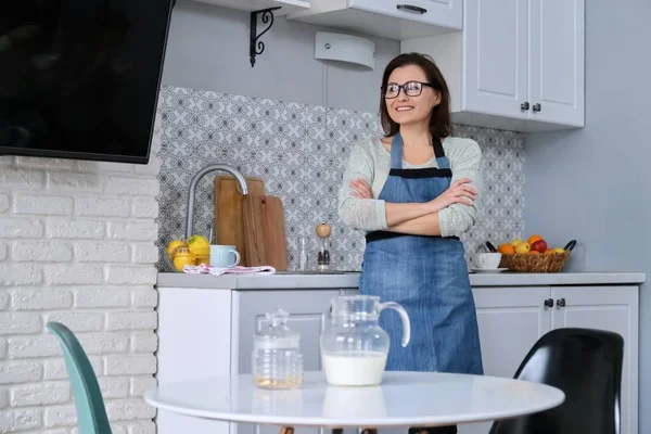 Домашній портрет зрілої жінки домогосподарки в фартусі на кухні — стокове фото