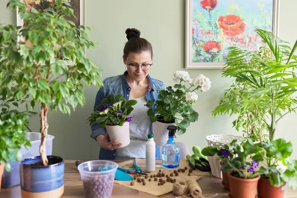 Vrouw die zorgt voor potplanten, herbeplanting, bemesting. — Stockfoto