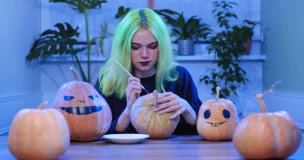 Voorbereiding van Halloween feest, jong tiener meisje met eng heks make-up tekening op pompoenen — Stockvideo