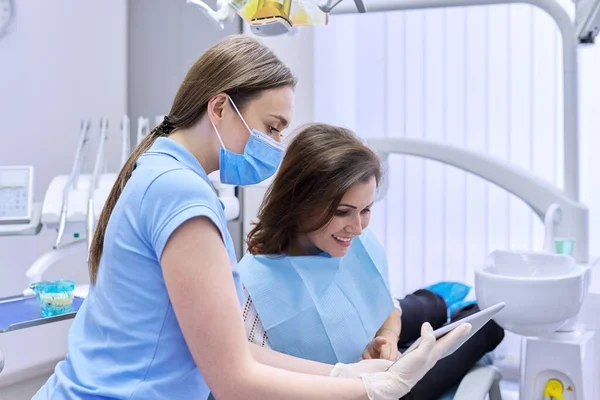 Стоматология, стоматологическое лечение, женщина врач-стоматолог консультирует пациента в кресле — стоковое фото