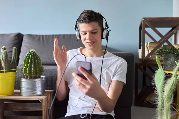 Мальчик-подросток в наушниках со смартфоном делает видеозвонок — стоковое фото