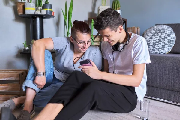 Feliz falando mãe e filho adolescente, pai e filho sentado em casa olhando para o smartphone — Fotografia de Stock