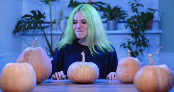 Halloween party, dospívající dívka s čarodějnice make-up sedí u stolu se slavnostní dekorativní dýně