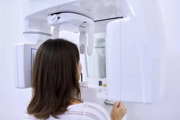 Woman patient in dental x-ray machine, back view