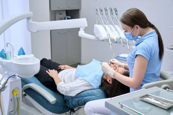 Vrouw arts tandarts behandeling van tanden aan patiënt in tandartsstoel — Stockfoto