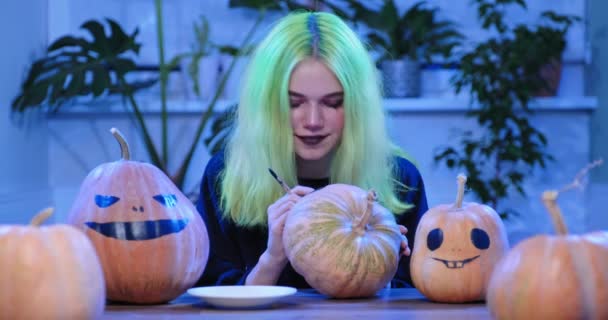 Підготовка вечірки на Хеллоуїн, молода дівчина-підліток з страшним макіяжем відьом на гарбузах — стокове відео