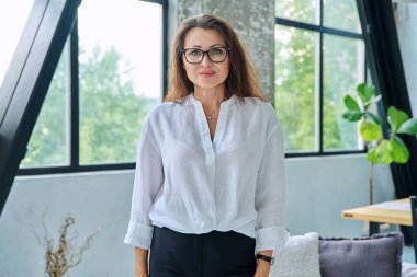 Beyaz gömlekli, gözlüklü, kameraya bakan orta yaşlı güzel bir iş kadını portresi. 40 'lı yaşlarda başarılı bir kadın. İş yönetimi kariyeri olgun insanlar