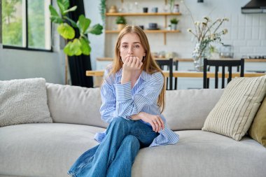 Üzgün, üzgün, üzgün, genç bir kadın. Kanepede oturuyor. Yüzü yakın plan. Duygular, sorunlar, ilişkilerde zorluklar, öğrenim, aile