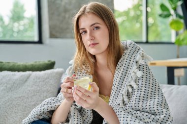 Genç bir kadın kendini bir fincan sıcak çayla limonla ısıtıyor. Yazın yüksek sıcaklıkta viral enfeksiyon kapıyor. Mevsimsel viral hastalıklar, hastalık, tedavi, sağlık gençliği kavramı