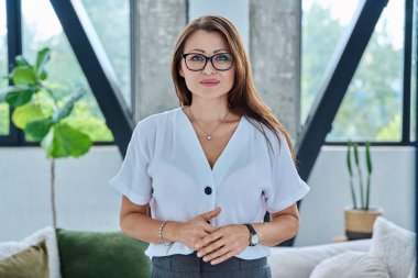 Kameraya bakan orta yaşlı güzel bir iş kadınının portresi. Ofiste elleri bağlı, 40 'lı yaşlarda kendinden emin bir kadın. İş yönetimi kariyeri olgun insanlar