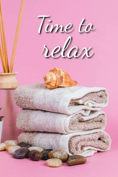Pembe arka planda spa malzemeleri, mum, taş, havlu ve çiçekler
