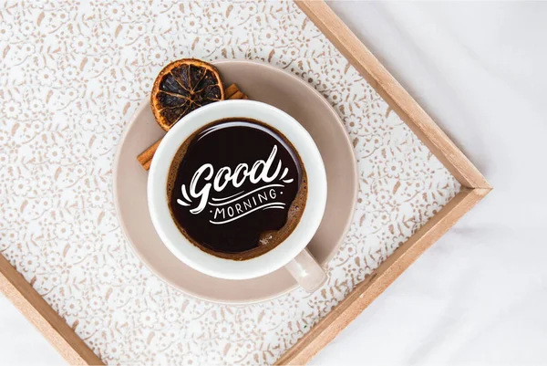 Fresh morning coffee on a board on a bed sheet with the text