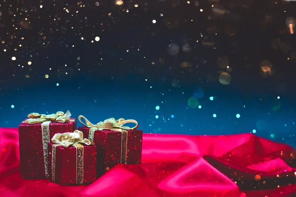 Funkelnde Rote Geschenkschachteln Mit Weihnachtsbeleuchtung Auf Rotem Seidenstoff Und Blauem — Stockfoto
