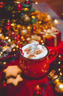  Kırmızı fincan sıcak kahve, Noel ışıkları, taze kurabiyeler, krema, tarçın ve saman.