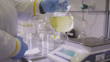 aygıt ve uzakta alır ölçme üzerinde sarı sıvı ile büyük ampul mavi eldiven içinde laboratuar asistanı el koyar