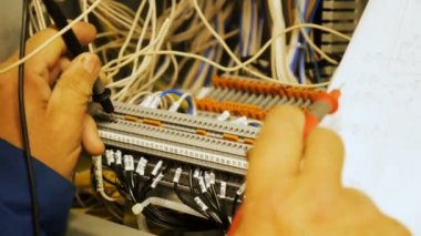 Üniformalı closeup vasıflı işçi geçiş panosunda kağıt teknik düzeni kullanarak doğru elektrik devresi oluşturur