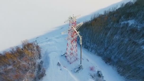 凍った湖に近い冬の森の中で空撮電気伝達タワー建設現場を鼓舞 — ストック動画