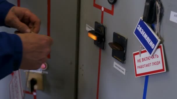 Electrician hangs up warning sign on switchboard door — Stock Video