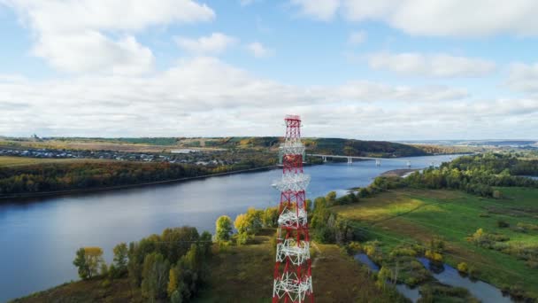 Línea aérea de alto voltaje contra puente distante sobre el río — Vídeos de Stock