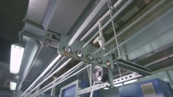 Стеклянные нити крупным планом растягиваются через отверстия для ткацкого станка — стоковое видео