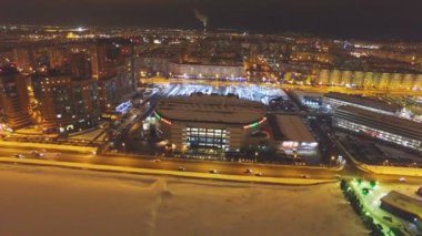 Harika üst görünümü hareket modern arena bina karla kaplı ve donmuş gece şehir arasında geçmiş Nehri