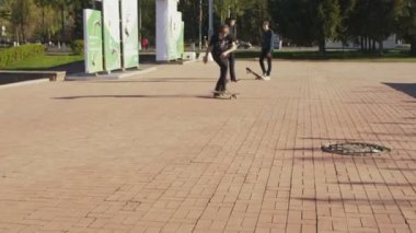 Adam kap ve siyah tişört sürmek hüner ve kaykay büyük şehir meydanında güneşli günde düşüyor