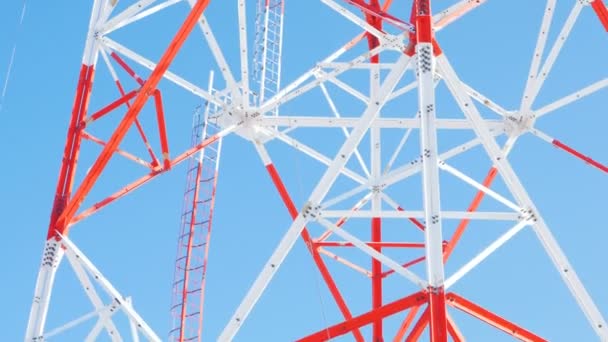 Red and white lacy metal transmission tower against sky — Stock Video
