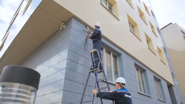 Lavoratore controlla il funzionamento della telecamera a circuito chiuso e collega tiene scala — Video Stock