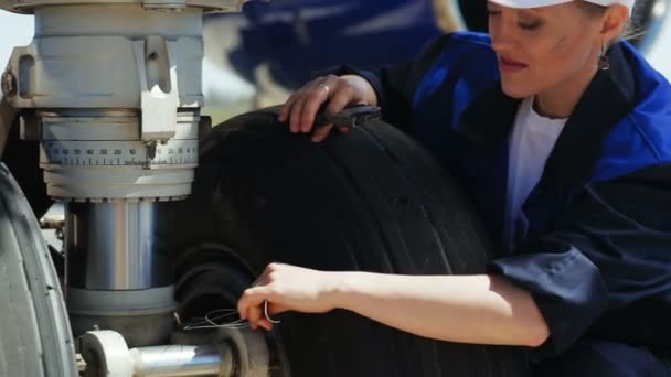 Employee makes measurements sitting near airplane wheel — Stock Video