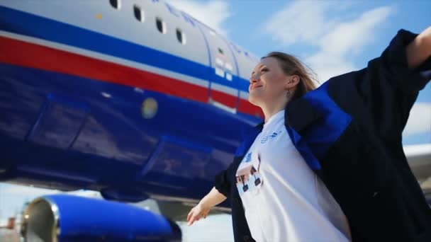 Sonriente chica pone manos contra el avión y el cielo — Vídeos de Stock