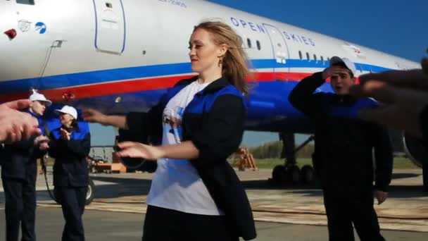 Trabajadores del aeródromo aplauden mujer bailando contra avión — Vídeos de Stock