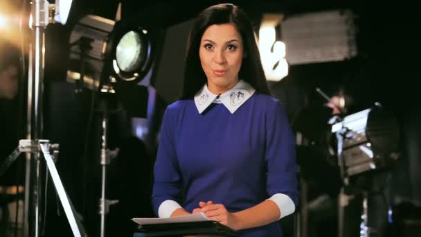 Apresentador de TV em blusa azul fala com o público no set — Vídeo de Stock